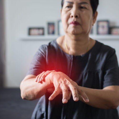 eine Frau hat Nervenschmerzen in der Hand. Sie hält die Hände nach vorne sie glühen leicht rötlich.