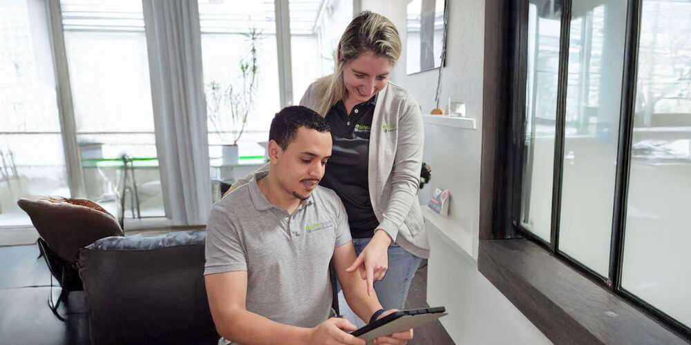 Das Team von Sanus Bodywork schaut geleinsam auf ein Tablet.