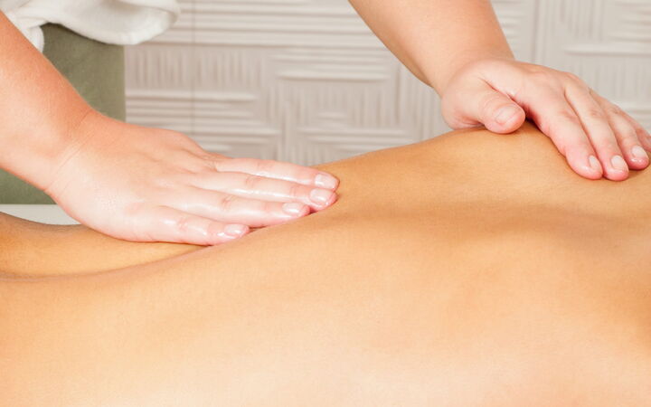 Eine Patientin liegt auf dem Bauch und erhält eine Rückenmassage.