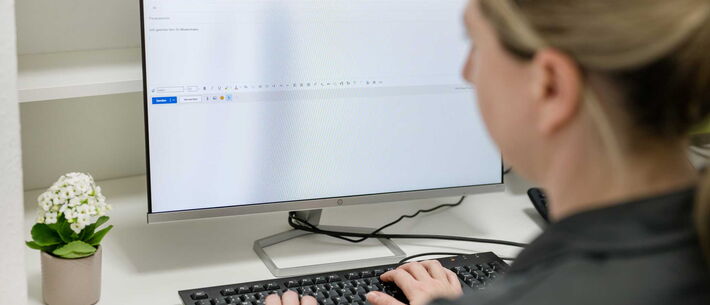 Eine Person schreibt eine E-Mail am Computer.